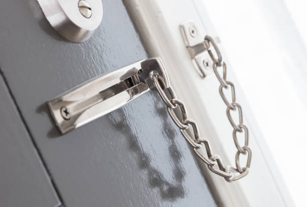 Door chain on a grey door, security measures