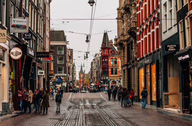 The famous Leidsestraat street with crowd of people in Amsterdam City Centre. Tourists and locals are walking, a tram is approaching on street.