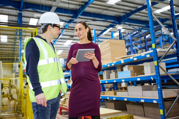 istock Pregnant businesswoman talking with warehouse worker 671360318