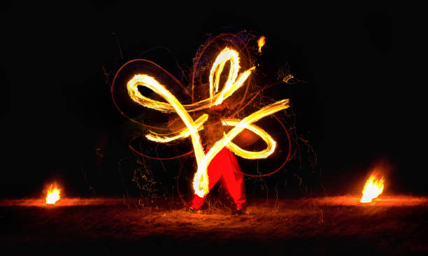 istock Man entertains the audience with the help of fire 671361372
