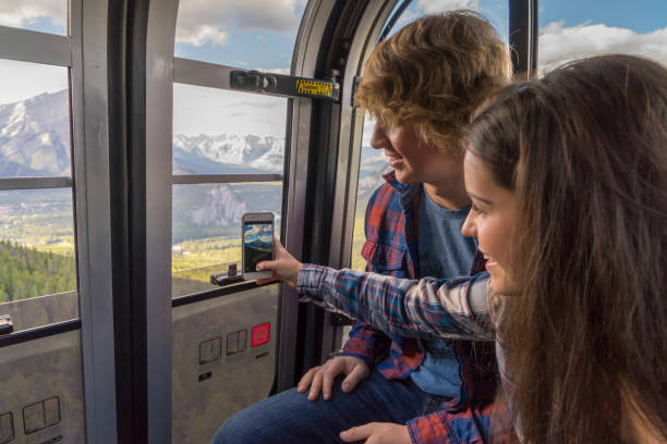 un couple d’adolescents prend une photo de téléphone intelligent depuis le téléphérique - banff gondola photos et images de collection