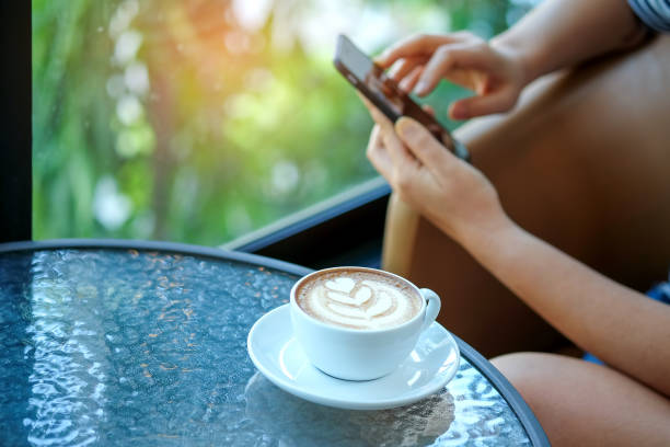 istock Women playing smart phone with coffee heart latte in hand. 671368340