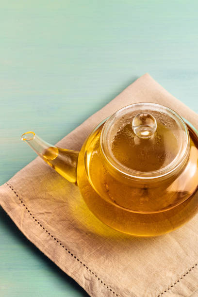 istock Teapot full of tea on teal texture with copyspace 671385960