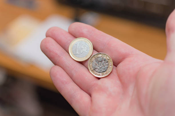 istock Holding 1 euro and 1 UK pound coin 671386072