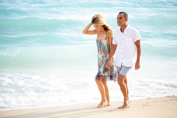 Happy senior couple walking hand-in-hand on the beach