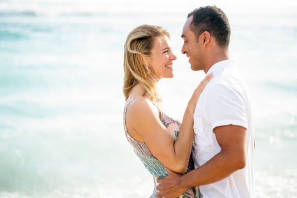 istock Middle-aged Couple Smiling and Embracing by Sea 671386272
