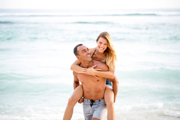 istock Happy husband carrying wife on shoulder at seaside 671386364