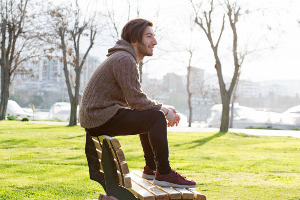istock Young man daydreaming on the bench in the park 671394336