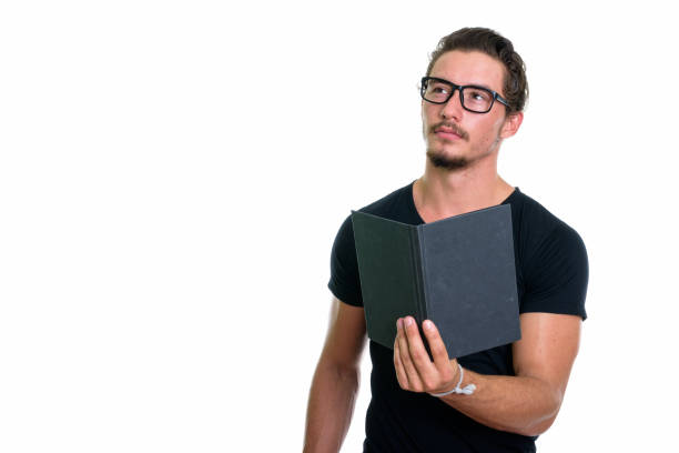 istock Studio shot of young handsome man holding book while thinking with eyeglasses isolated against white background 671400306