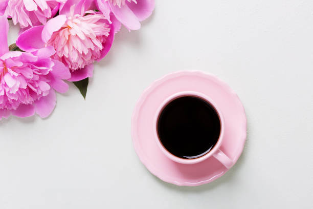 istock Cup of coffee and flowers (peonies) on light  grey table. 671400320
