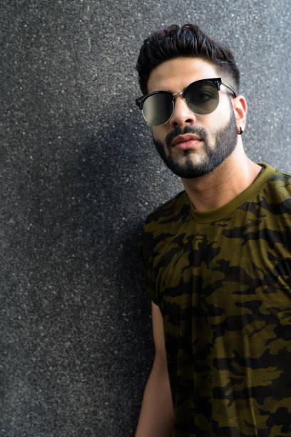 istock Young handsome Indian man thinking while wearing sunglasses against gray concrete wall 671404844