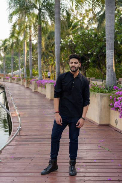 istock Young handsome Indian man thinking while standing on the boardwalk at quiet park in Bangkok Thailand 671404880