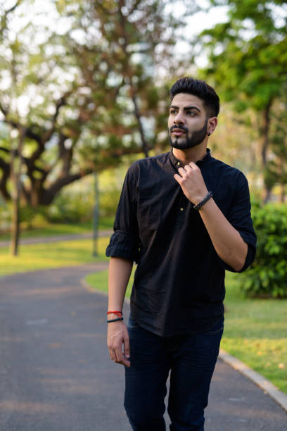 istock Young handsome Indian man thinking while walking on the road at the park 671404928