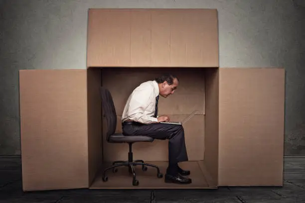 Man sitting in a box working on laptop computer