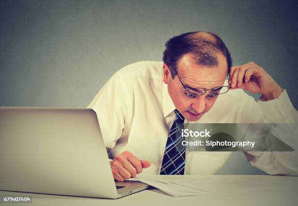 Foto de Homem De Negócio Surpreendido Confundido Que Olha Originais Executivos Envelhecidos Médios Corporativos Chocados Que Trabalham Em Sua Mesa No Escritório Que Revê O Documento e mais fotos de stock de Erro