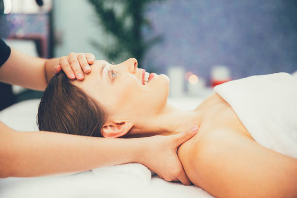 istock Smiling woman enjoying face and neck massage 671408182