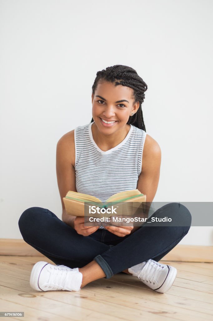 Femme noire souriante, assis sur le plancher avec livre - Photo de Adulte libre de droits
