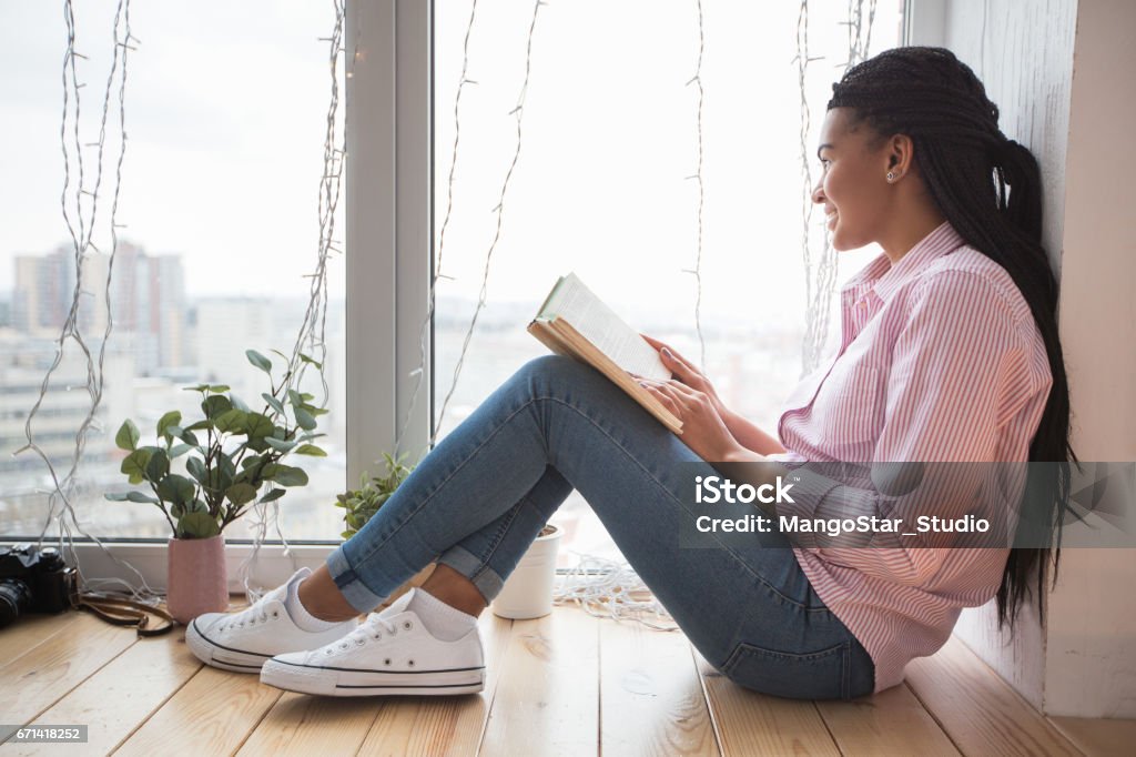 Femme pensive avec livre regardant dehors la fenêtre - Photo de Activité commerciale libre de droits