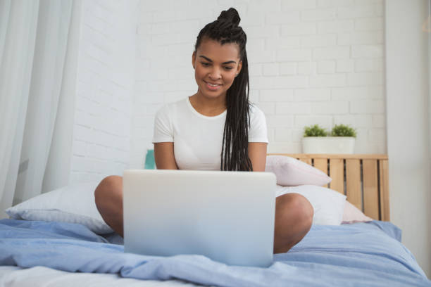 istock Smiling African woman reading email on laptop 671418332