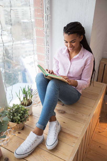 istock Smiling young woman enjoying favorite book 671418352
