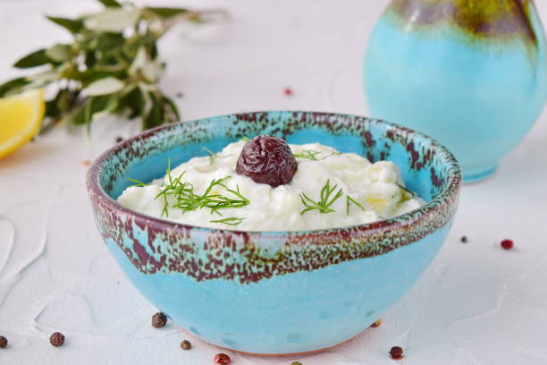 Homemade Greek traditional sauce tzatziki with cucumber, garlic, yogurt , olive oil and lemon in a traditional colored bowl on a white background. Healthy eating concept. Mediterranean lifestyle Homemade Greek traditional sauce tzatziki with cucumber, garlic, yogurt , olive oil and lemon in a traditional colored bowl on a white background. Healthy eating concept. Mediterranean lifestyle tzatziki stock pictures, royalty-free photos & images