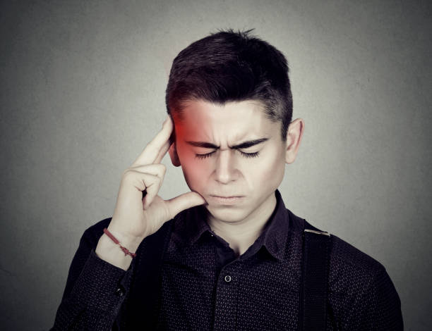 istock Man having a headache touching with hand temple colored in red 671430834