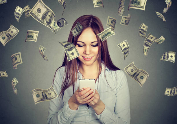 istock Young woman using looking at her smart phone under money rain 671430838