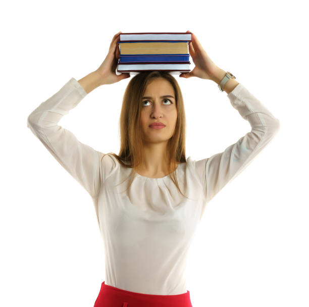 Student girl holds stack of books on head stock photo