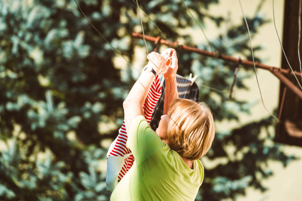 This photo captures a line of freshly washed children’s socks in pastel shades, gently swaying in the breeze on a clothesline secured with wooden clothespins. The soft natural light and shallow depth of field evoke a sense of calm, cleanliness, and domestic care. Perfect for illustrating themes like laundry, sustainable living, baby care, or everyday family routines in an eco-conscious household.
