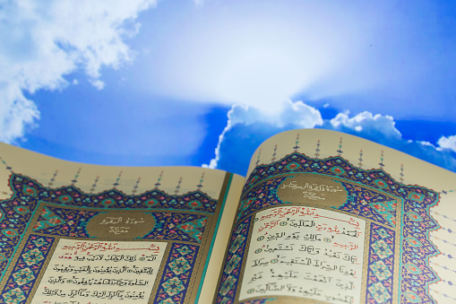 Opening pages of holy book Qur'an with clouds