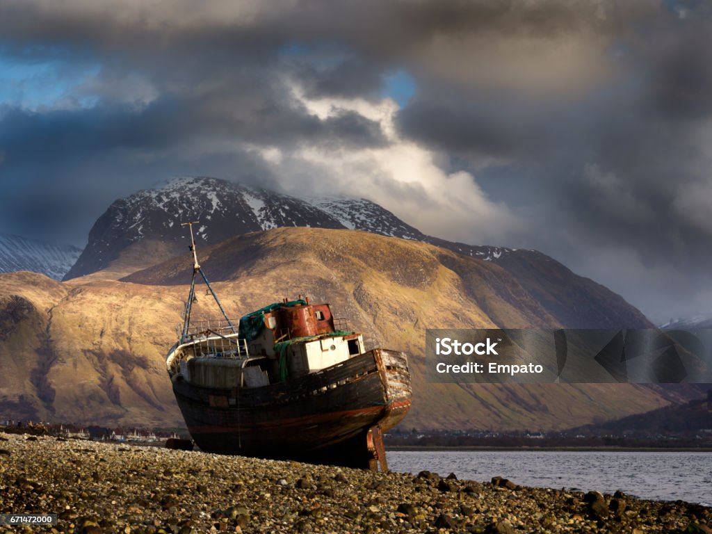 Long abandoned boat, Corpach. A view towards Ben Nevis from the beach at Corpach, near Fort William in the highlands of Scotland with an old, long abandoned boat resting on the beach. Ben Nevis Stock Photo