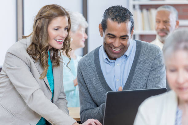 istock Mid adult female technology instructor teaches class at senior center 671472904