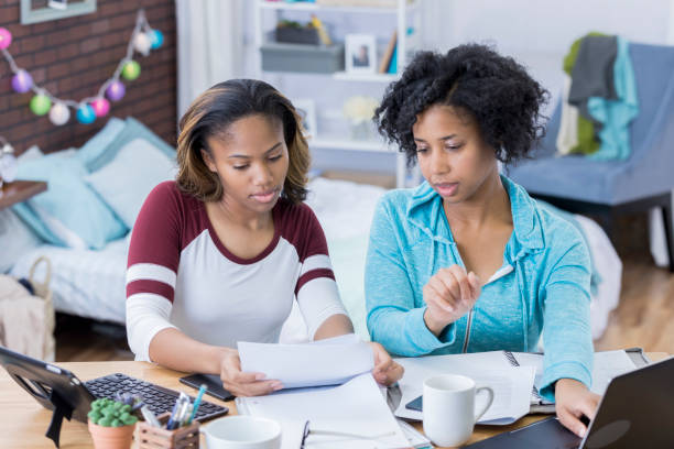 Young women work together on something in college dorm room
