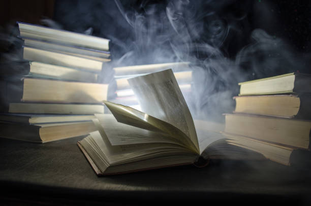 istock Many old books in a stack. Knoledge concept. Books on a dark background with smoke elements. Bewitched book in center 671473056