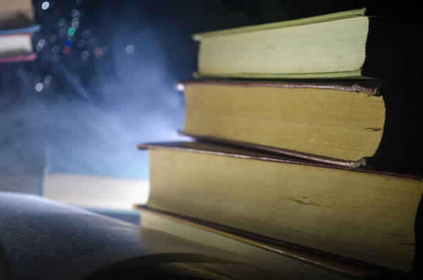 istock Many old books in a stack. Knoledge concept. Books on a dark background with smoke elements. Bewitched book in center 671473066