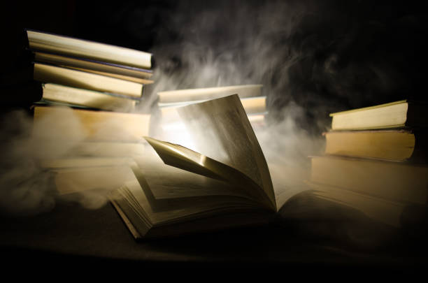 istock Many old books in a stack. Knoledge concept. Books on a dark background with smoke elements. Bewitched book in center 671473106