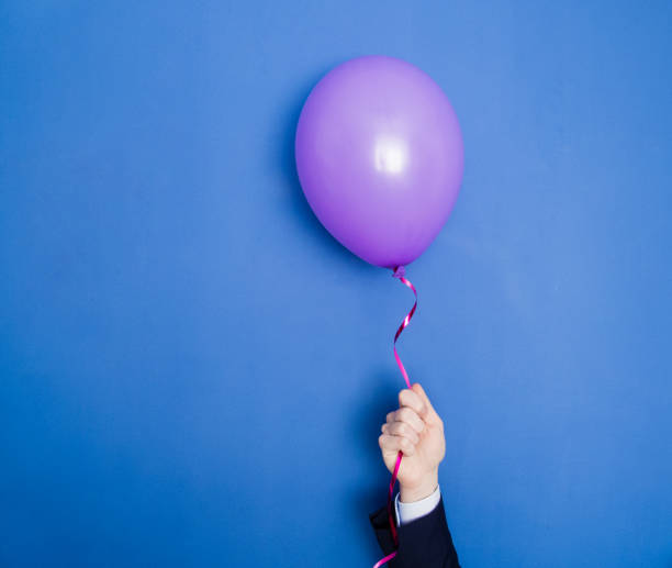 Hand in a suit holding flying up balloon.