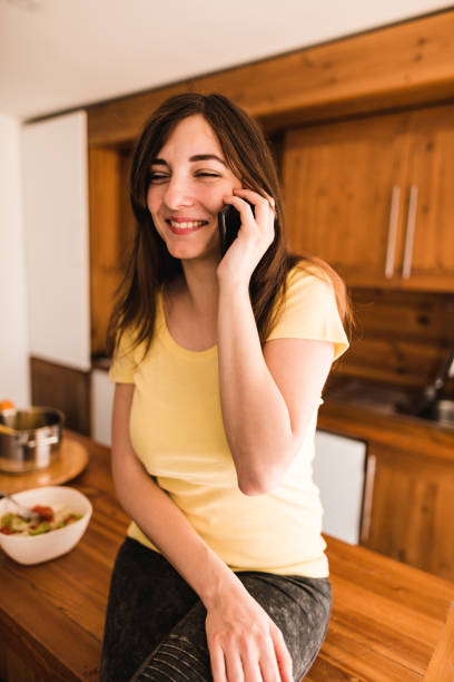 istock woman on the phone in the kitchen 671493392