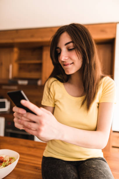 istock woman on the phone in the kitchen 671493450