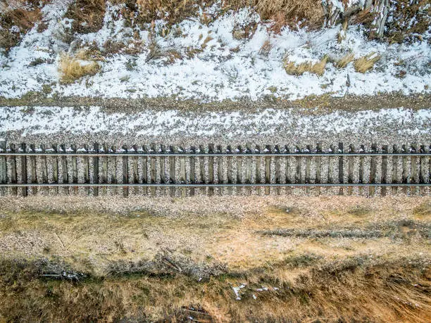 aerial view of single railroad tracks in back country with some weeds and snow