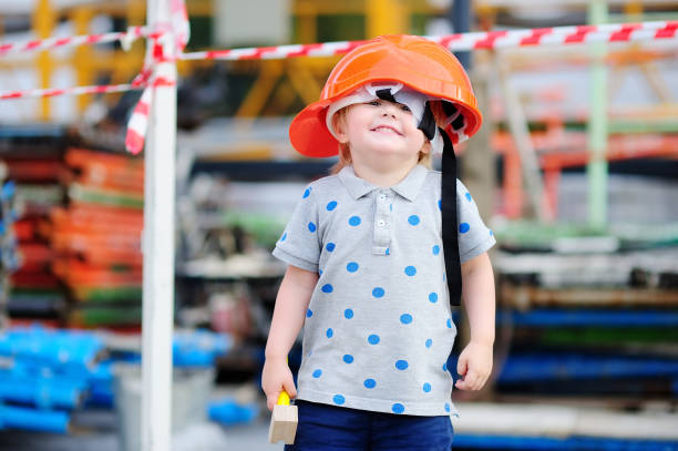 piccolo costruttore divertente in hardhat con martello che lavora all'aperto - child building activity construction engineer foto e immagini stock