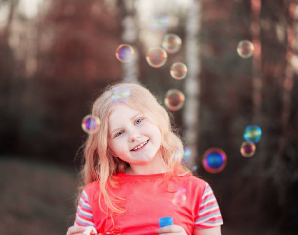 istock girl blowing soap bubbles outdoor at sunset 671504190