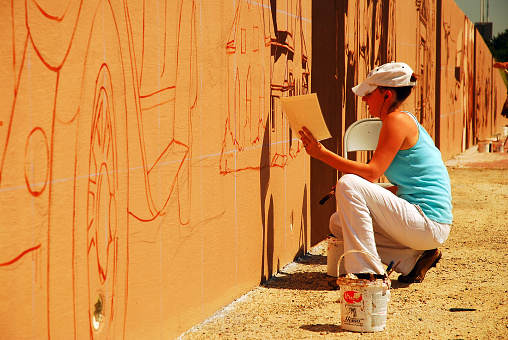 Denton, TX, USA May 19 2008 A young woman works on a mural depicting the history of Denton Texas near the on ramp for on a wall along Interstate 35
