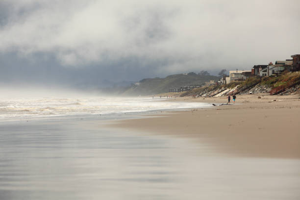 Watsonville,California,USA- February 20,2017:  Coast of Central California. Stormy misty atmosphere and sky. Sand,homes and people in background.  Couple Mid frame
