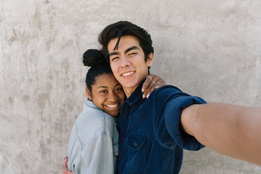 A teen couple takes a fun selfie.