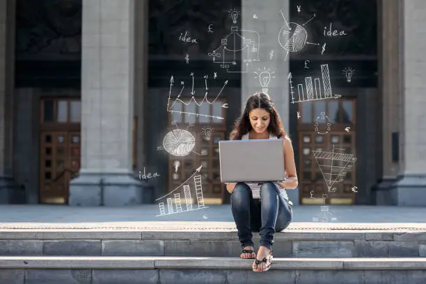 Photo of Young woman with laptop sitting on the stairs, near university