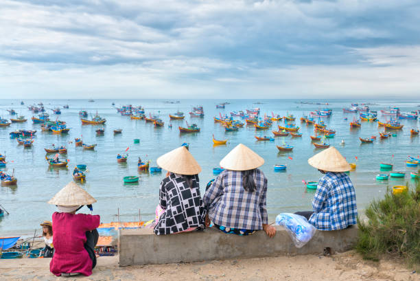 A group of vietnamese women waiting for the fishing boat Mui Ne, Vietnam - February 19th, 2017: A group of vietnamese women waiting for the fishing boat on the port in a small village close to Mui Ne, Vietnam. mui ne bay photos stock pictures, royalty-free photos & images