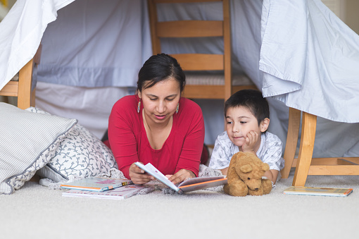 Native American mom reads with her son under makeshift fort in living room