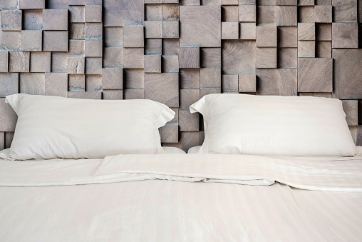 white bed with 2 pillows on wooden wall room background