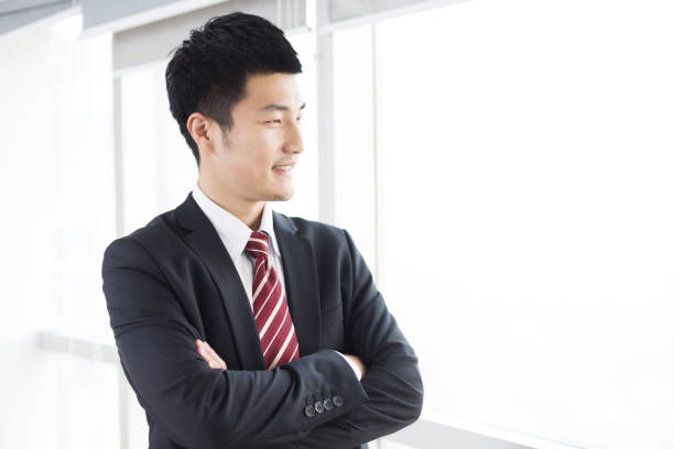 istock handsome asian businessman stands near window 671565362